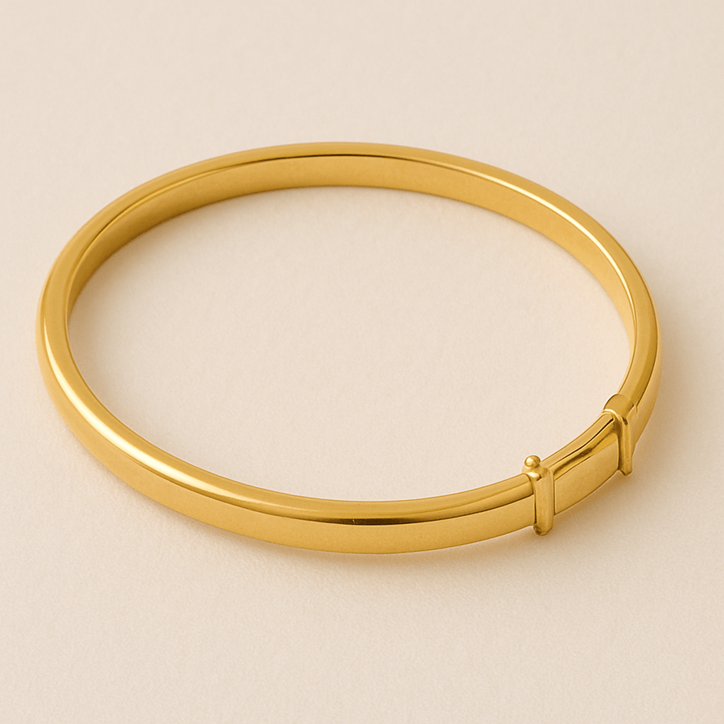 Simple gold bangle with sleek clasp, shown on a beige surface.