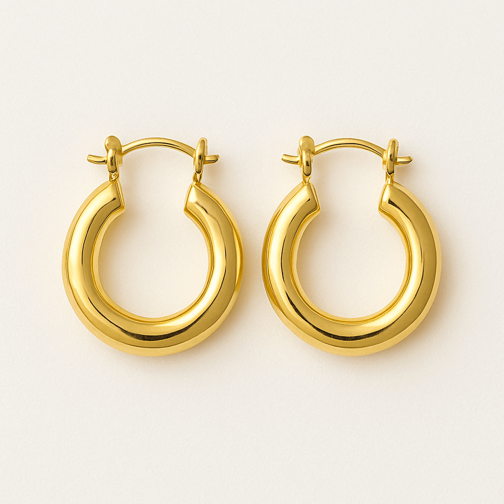 Pair of chunky gold hoop earrings on a cream background.