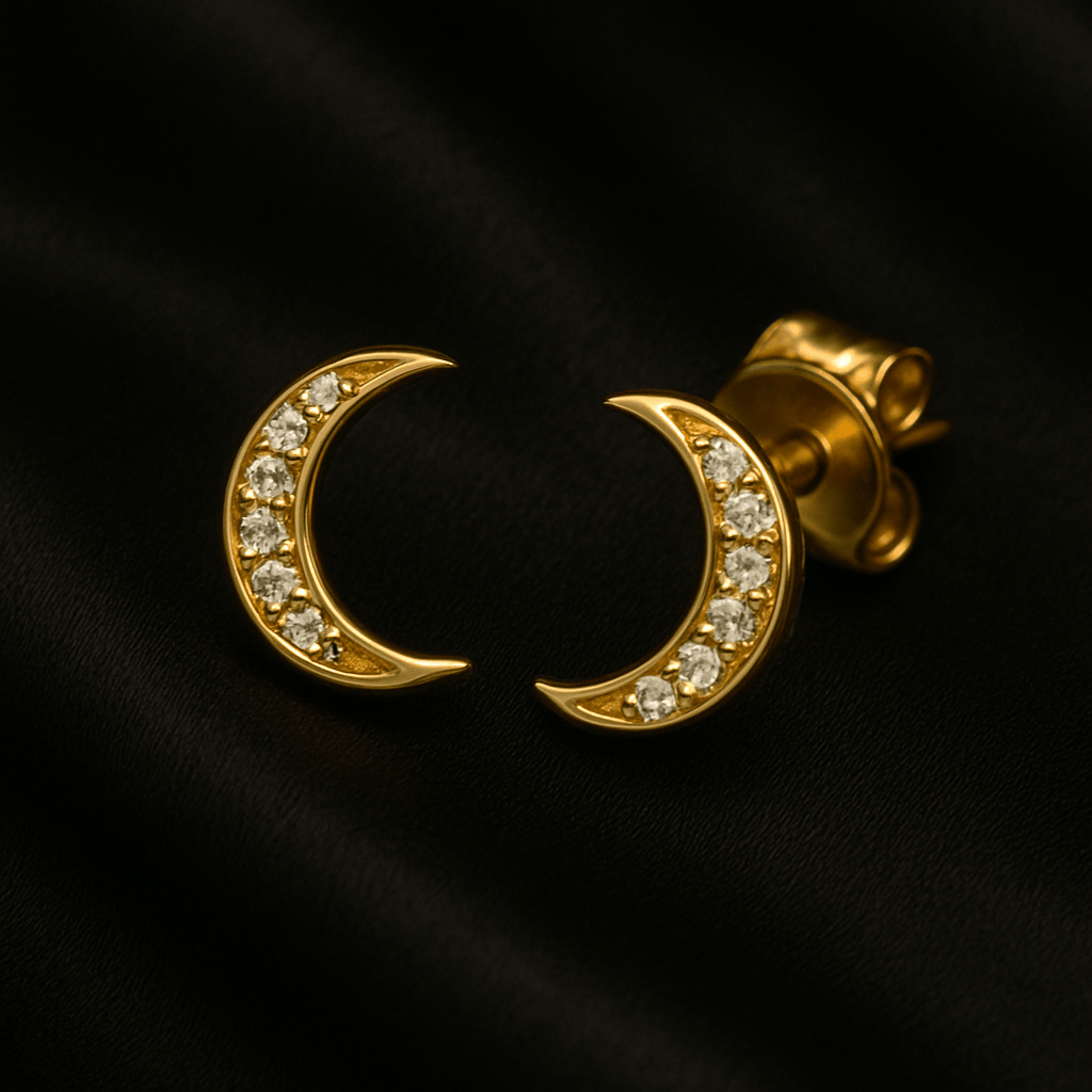 A pair of crescent-shaped gold earrings encrusted with white gemstones.